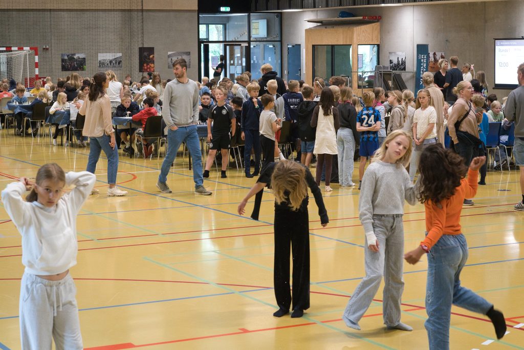 students in a school gymnasium participating in a chess event