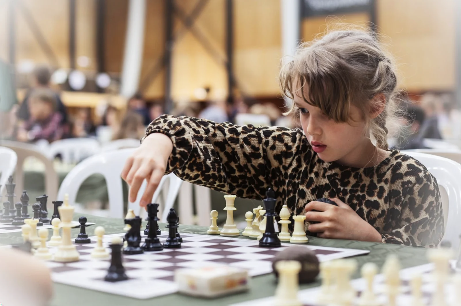 A child concentrating on a chess move during a learning activity.